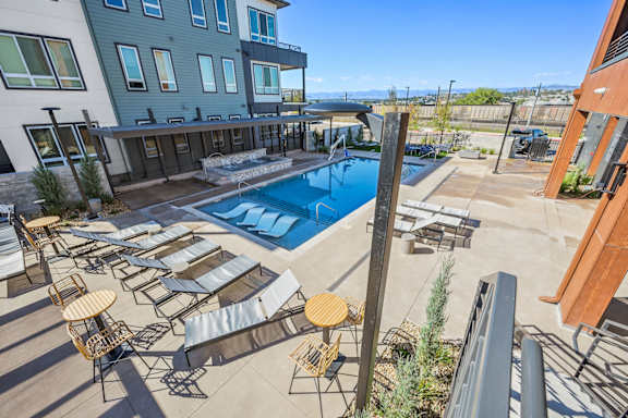 Pool deck with lounge chairs and surrounding buildings at Sequel Homes Apartments, Englewood, Colorado