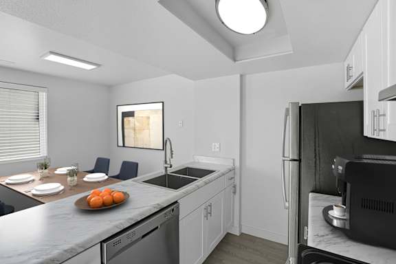 A kitchen with a refrigerator, sink, and a dining table set for two. at Park Station Apartments, Midvale, 84047