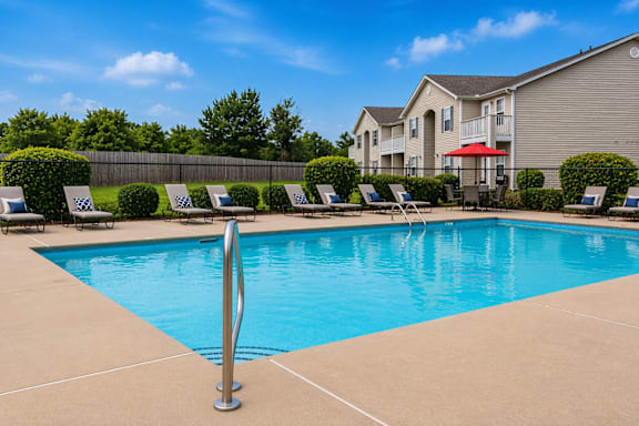 A swimming pool surrounded by lounge chairs and a fence.