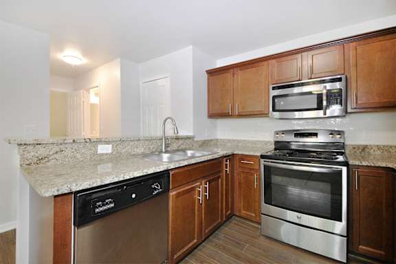 A kitchen with a stove, oven, sink and cabinets.
