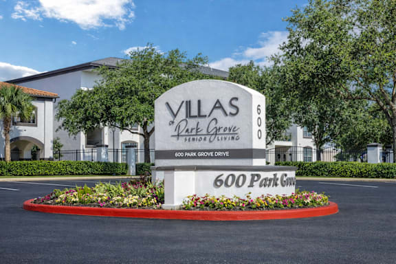 A sign for Villas at Park Grove in front of a building.