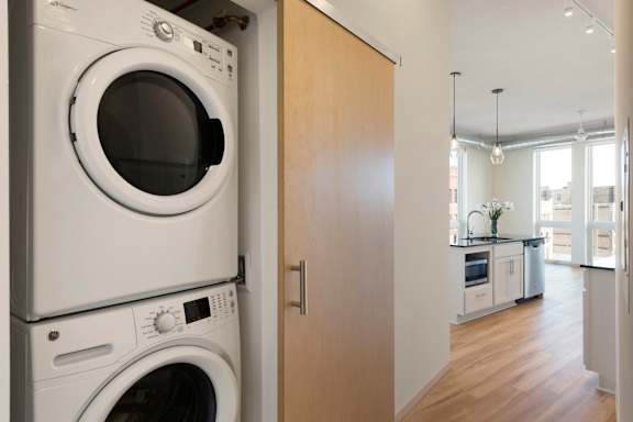 A white washing machine and dryer stacked on top of each other in a kitchen.