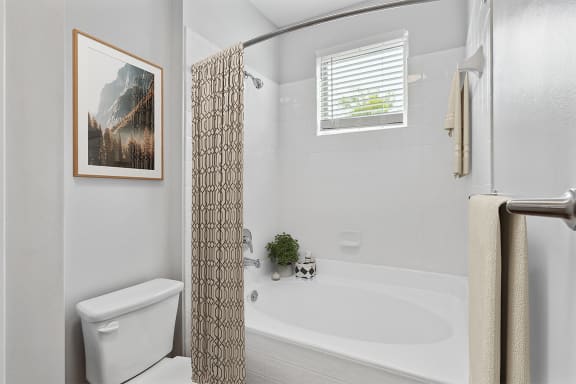 a bathroom with a white toilet next to a bathtub with a shower curtain at Two Addison Place, Pooler, 31322