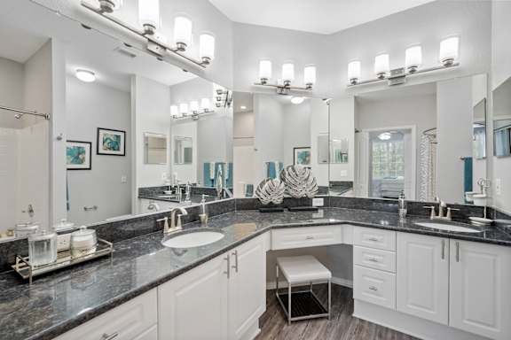 A bathroom with white vanity, black counters and large mirrors