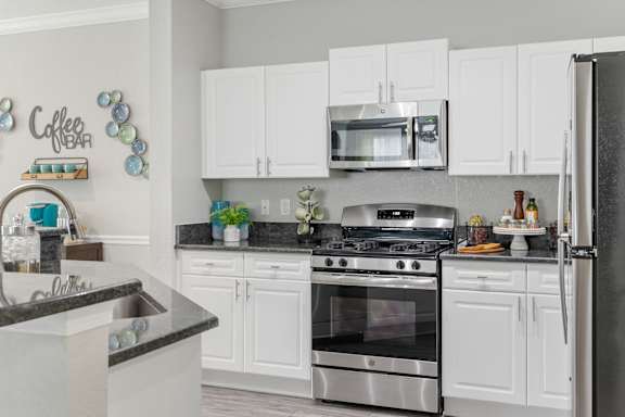 A kitchen with white cabinets and a black countertop.