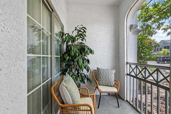 A balcony with a chair and a plant.