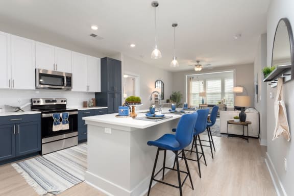 an open kitchen with an island and blue bar stools at Bristol at New Riverside, Bluffton