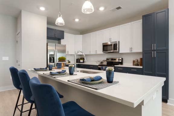 an open kitchen with a large island with blue chairs at Bristol at New Riverside, Bluffton, 29910