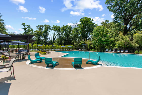 a swimming pool with umbrellas and chairs around it at Padonia village with splash pad and lounge seating