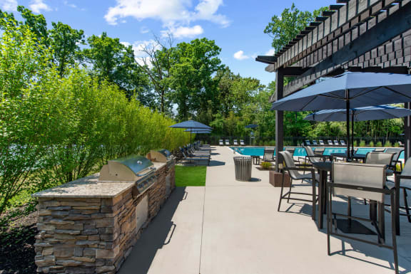 a patio with tables chairs and umbrellas and a pool at Padonia Village Apartments, Timonium, MD