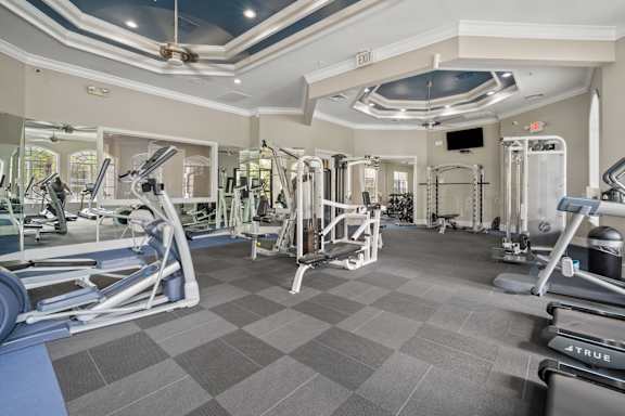 A gym with a variety of equipment including treadmills, weights, and exercise machines.