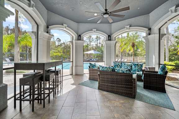 A patio with a table and chairs overlooking a pool.