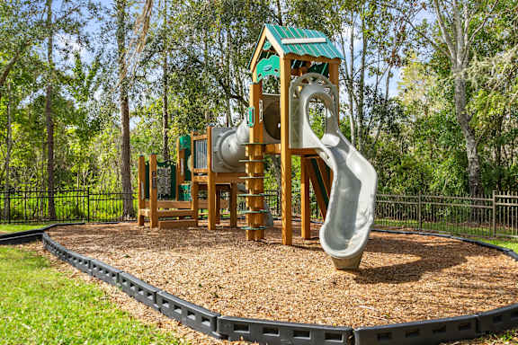 A playground with a green roofed structure and a grey slide.
