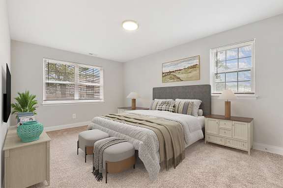 A bedroom with a large bed, a bench, and a side table with a plant on it.