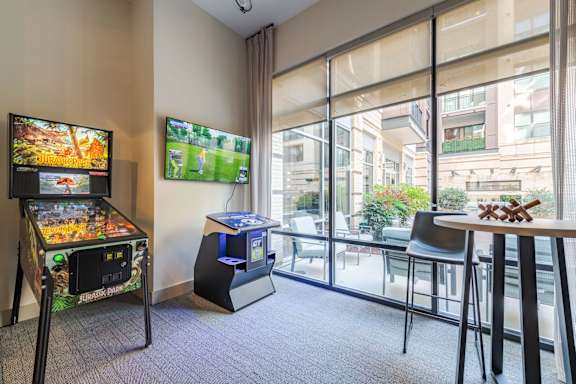 A room with a pinball machine and a TV showing a game.