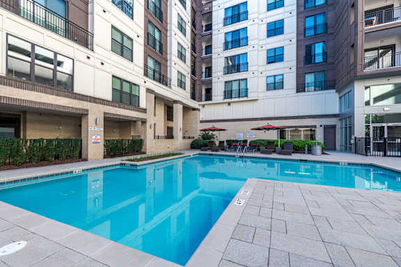 A large swimming pool in front of apartment buildings.