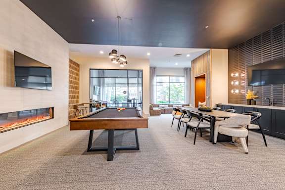 A room with a pool table, a fireplace, and a dining table.