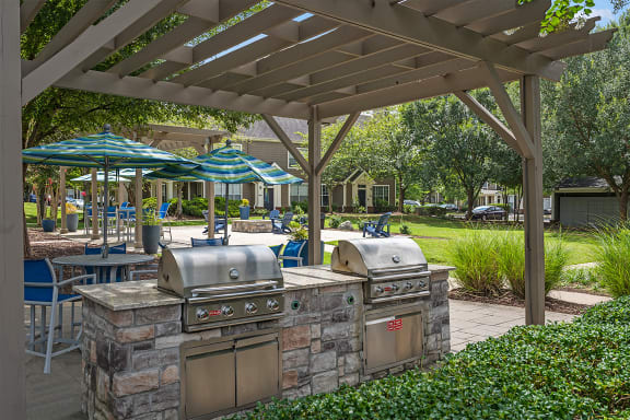an outdoor kitchen with grills and umbrellas