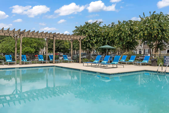 a swimming pool with blue chaise lounge chairs and a pergola with trees in the at Fortress Grove, Murfreesboro, Tennessee