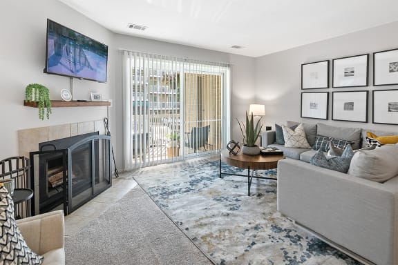 an open living room with a fireplace and a sliding glass door at McDonogh Township Apartments, Owings Mills