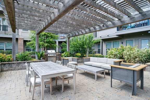 A patio with a table and chairs under a wooden pergola at The Linden Apartments, Davidson, NC, 28036