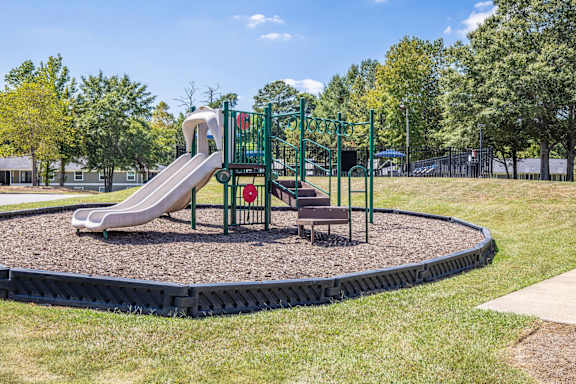 A playground with a green slide and a red sign.