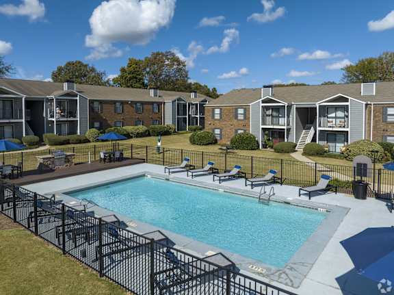 A pool surrounded by chairs and a fence.