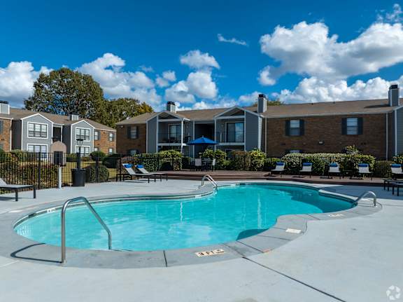 A swimming pool surrounded by a fence and chairs.