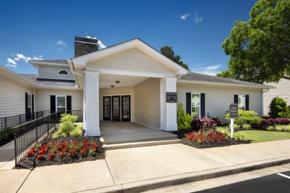 the front of a white building with a porch and a sign