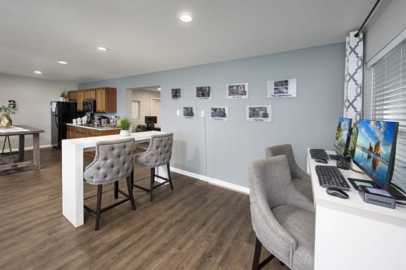 a home office with a desk and chairs and a kitchen
