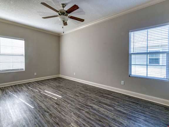 A room with a ceiling fan and wood flooring.