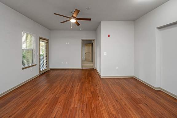 A room with a ceiling fan and wooden floors.