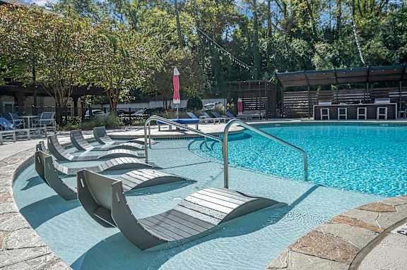 A pool with a red flag and lounge chairs.