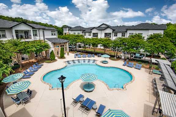 A large swimming pool surrounded by lounge chairs and umbrellas.