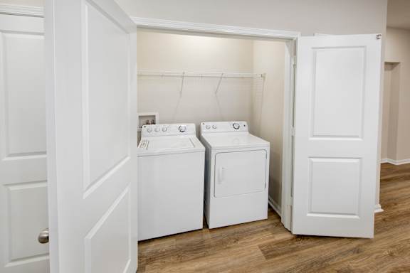 A white door is open to a laundry room with two washing machines.