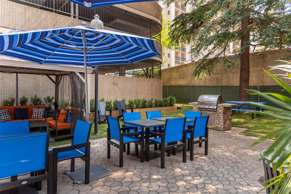 a patio with tables with chairs and umbrellas and a grill