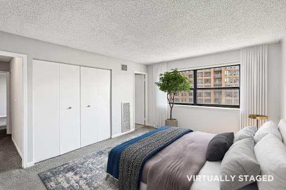 A bedroom with a bed, a chair, and a window with a view of a building outside.