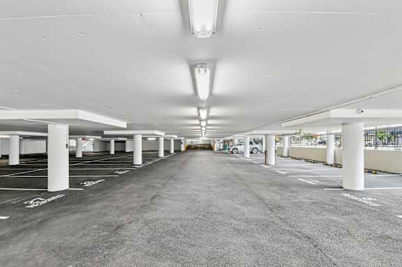 A parking garage with multiple parking spaces and a few cars parked.