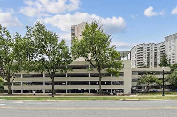 A parking garage with trees in front of it.