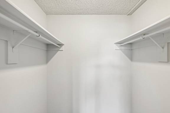 A white wall with two shelves on top.
