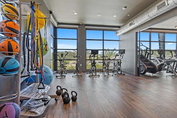 the gym with floor to ceiling windows and a view of the city