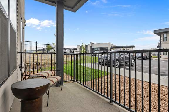 a balcony with chairs and a table overlooking a parking lot