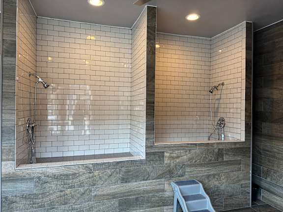 A bathroom with a tiled shower and a bench.