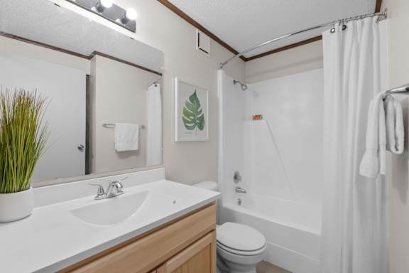 A white bathroom with a toilet, sink, and shower.