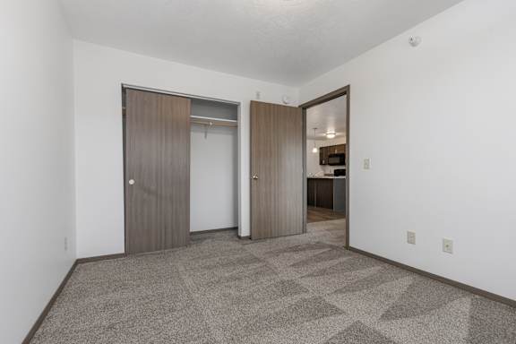 A room with a carpeted floor and two doors.