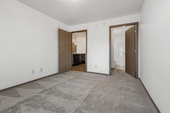 A room with a carpeted floor and two doors.