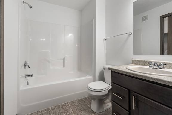 A white toilet sits next to a white bathtub in a bathroom.