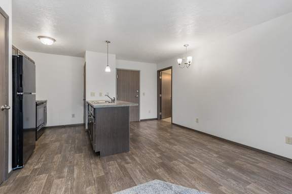 A kitchen with a refrigerator, sink, and cabinets.