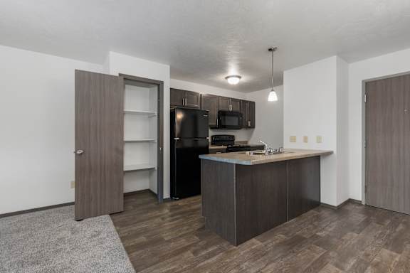 A kitchen with a brown door and a black fridge.