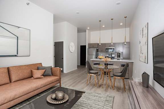 A modern living room with a brown sofa and a glass coffee table.